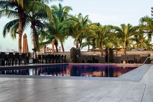 Una piscina con sillas de descanso y palmeras.