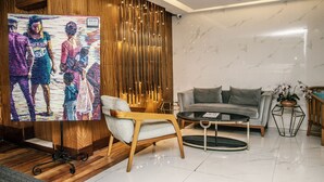 Un salon moderne avec un mur d’accent en bois, un canapé gris, une chaise en bois, une table basse ronde et une plante en pot.