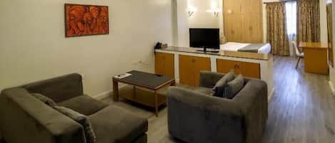A living room with two sofas, a coffee table, a TV, and a wooden cabinet.