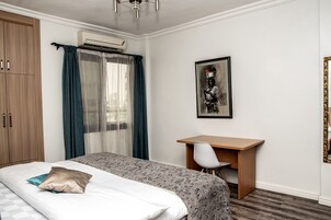 Una habitación de hotel con una cama, un escritorio y un armario.