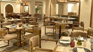 Un espace de restauration moderne doté de plusieurs tables et chaises, avec un plafond au design géométrique et un éclairage chaleureux.