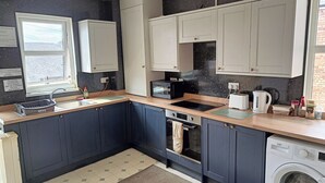 A compact kitchen with a sink, stove, toaster, and washing machine. - Avenue Road (Gateshead)