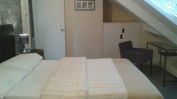 Un dormitorio con cama, escritorio, silla y tragaluz.