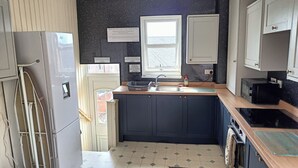 A compact kitchen with a sink, a microwave, and a refrigerator. There are signs on the wall with rules for guests. - Avenue Road (Gateshead)