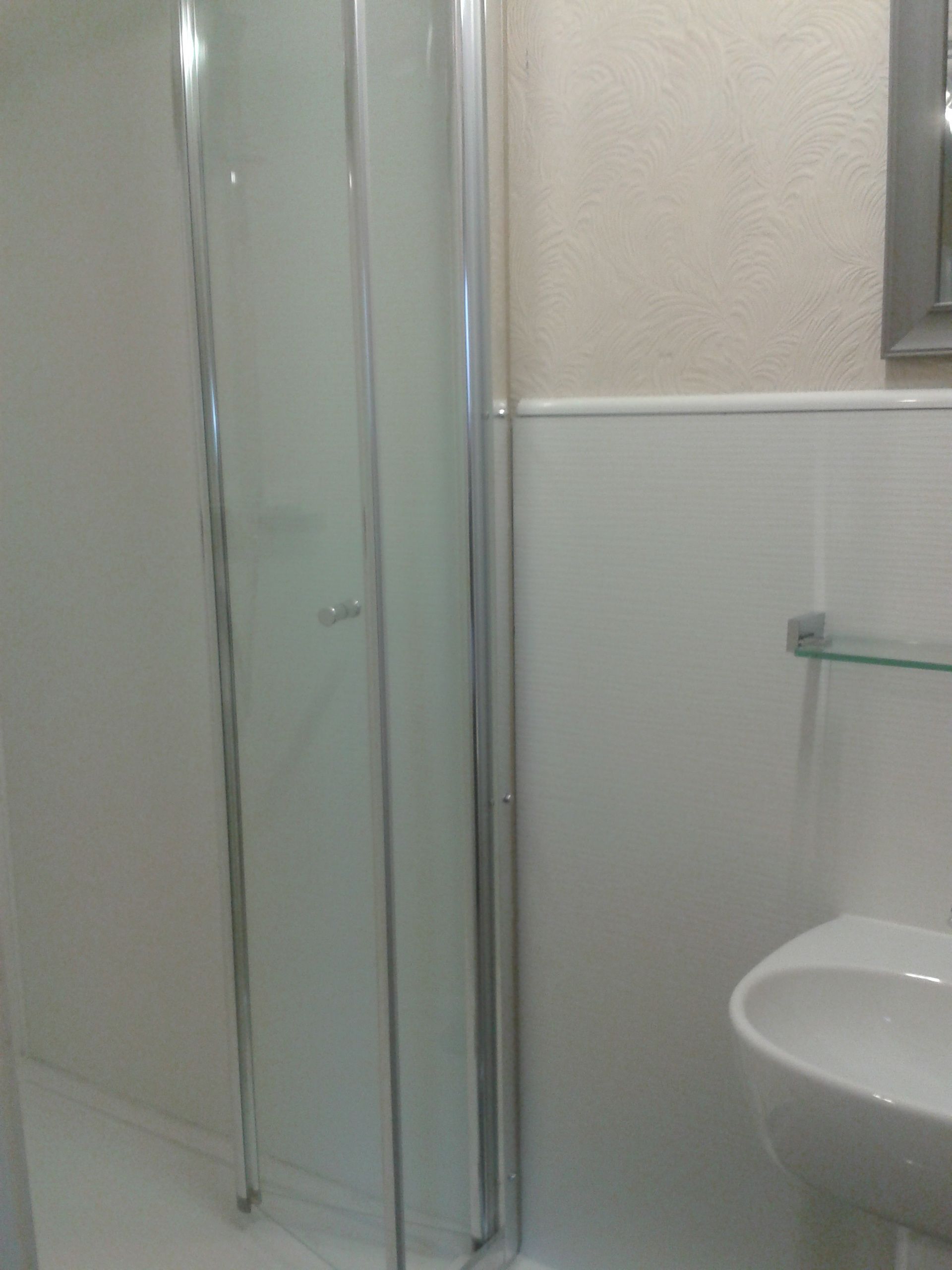 A bathroom with a glass shower enclosure, a white sink, and a mirror above the sink.