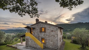 A stone house with a yellow staircase, surrounded by greenery and hills. - Villa Lavanda Todi, countryside casale with private pool in the heart of Umbria (Canonica, PG)