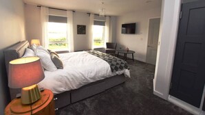 Une chambre à coucher avec un lit, une chaise, un téléviseur et une porte.