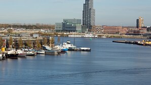 A waterfront cityscape with modern buildings, a marina with boats, and a clear sky. - Numa Amsterdam Docklands (Amsterdam)