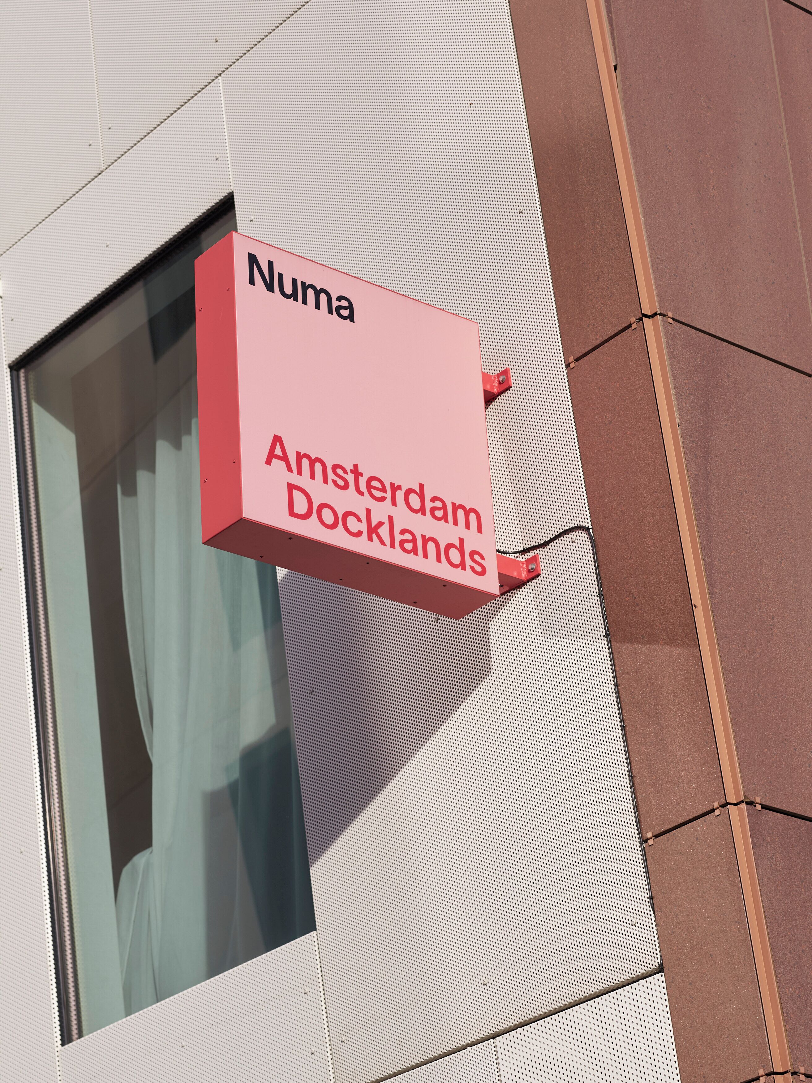 A sign for 'Numa Amsterdam Docklands' mounted on a building.