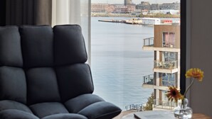 A modern living room with a view of a waterfront and buildings across the water. - Numa Amsterdam Docklands (Amsterdam)