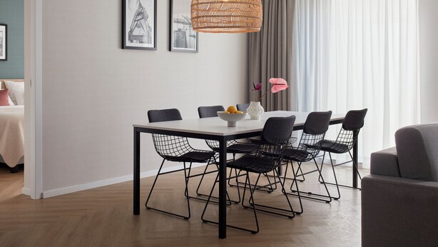 A modern dining area with a white table, black wireframe chairs, and a woven pendant light. - Numa Amsterdam Docklands (Amsterdam)