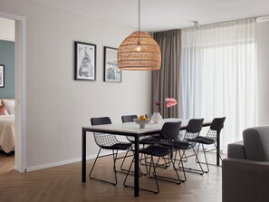 A modern dining area with a white table, black wireframe chairs, and a woven pendant light. - Numa Amsterdam Docklands (Amsterdam)