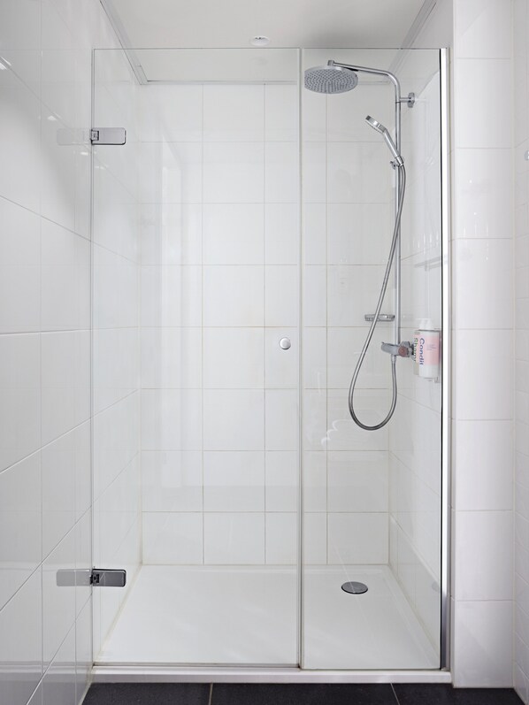 A glass-enclosed shower with a handheld showerhead and a wall-mounted faucet. - Numa Amsterdam Docklands (Amsterdam)