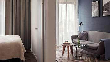 A hotel room with a bed, a sofa, a small table, and a rug.