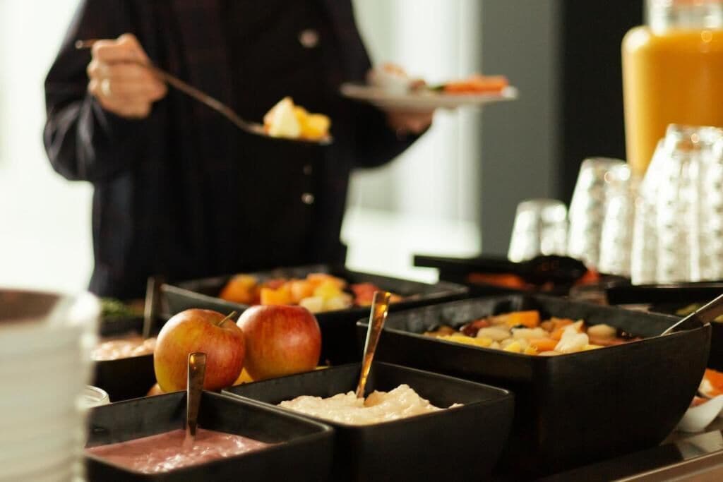 A buffet with various food items and a person serving.