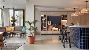 A modern interior with a curved bar, seating area, and a large window. - Numa Amsterdam Docklands (Amsterdam)