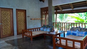 A room with a wooden bench, a table, and two doors with woven patterns. - Sinag Hostel - Adults Only (General Luna)