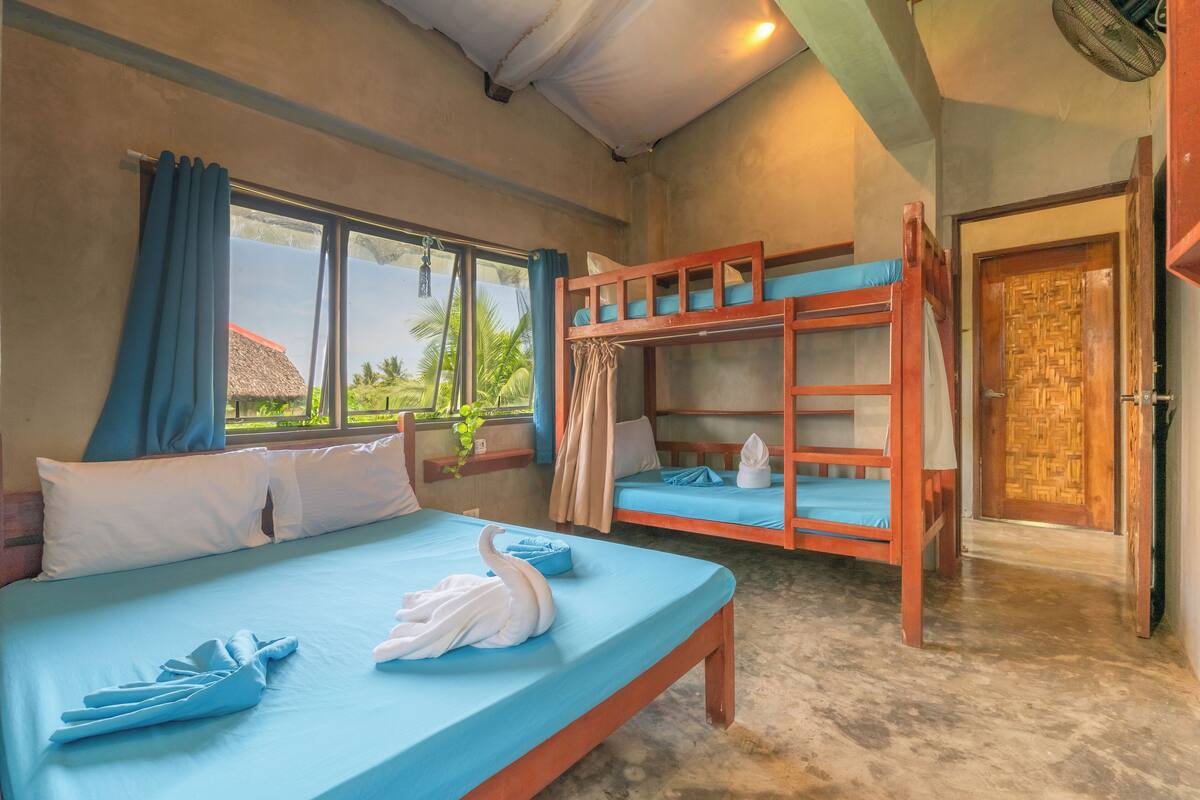 A room with a bed, a bunk bed, and a window with curtains.