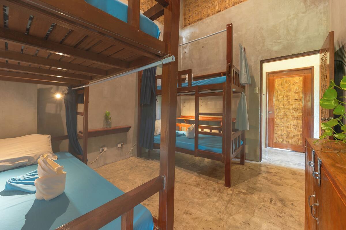 A room with bunk beds, a wooden cabinet, and a door with a woven pattern.