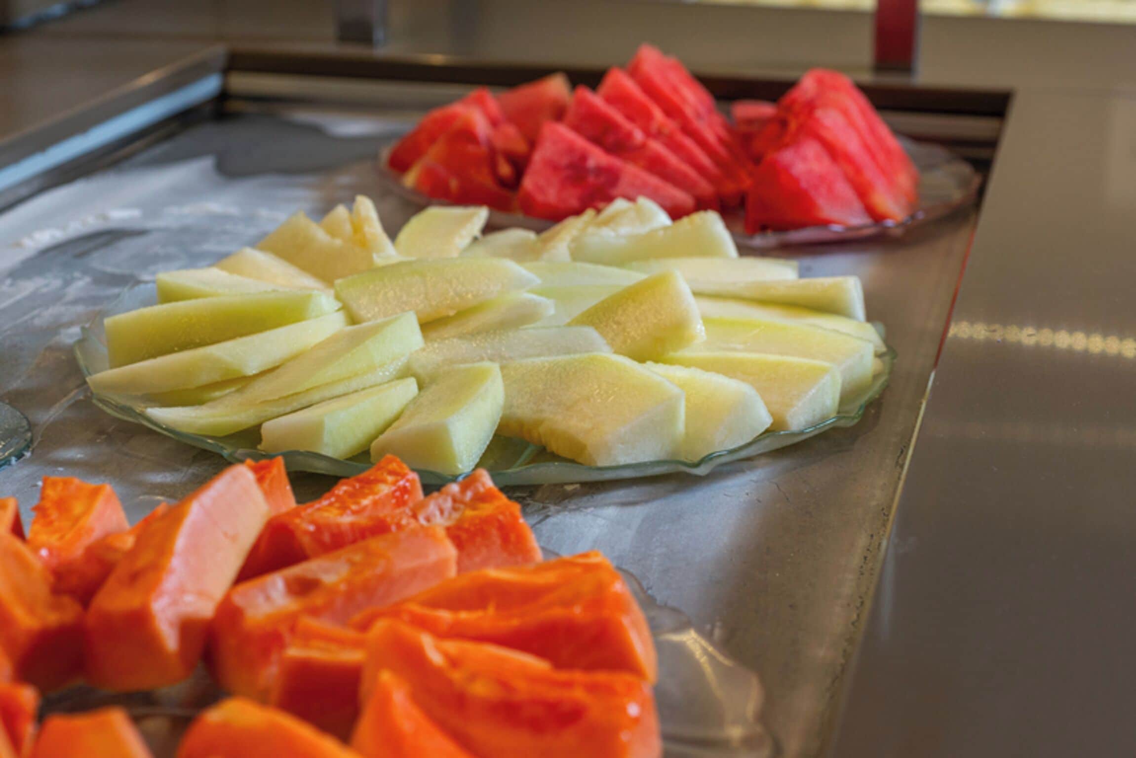 Una bandeja con frutas cortadas, como sandía, melón y papaya.