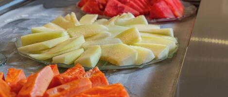Una bandeja con frutas cortadas, como sandía, melón y papaya.