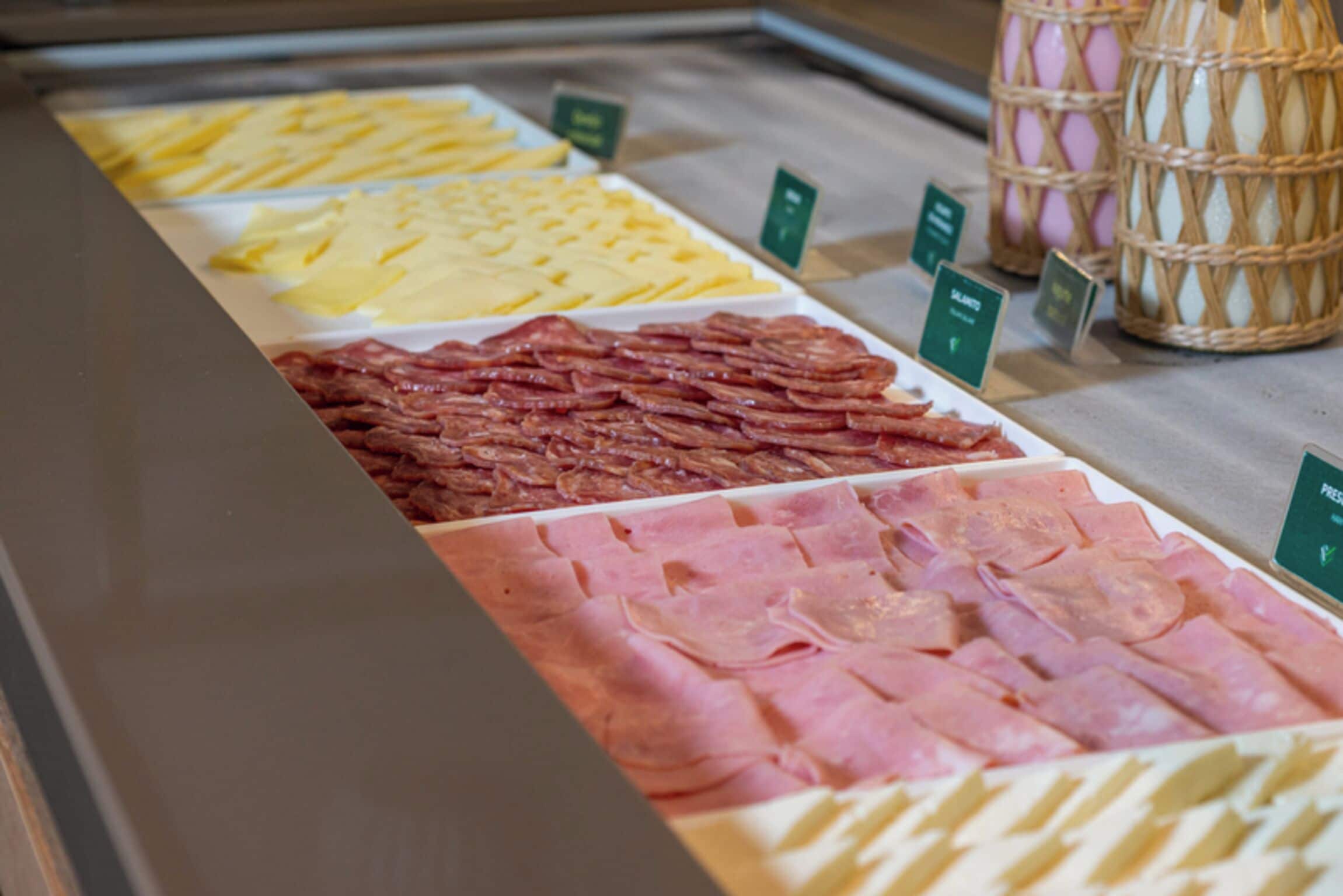 A deli counter with various types of sliced meats and cheeses.