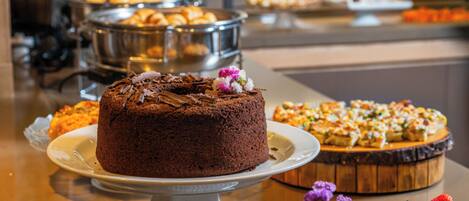 Un bufé con diversos postres, incluyendo pastel de chocolate, pastelería y tartaletas de fruta.