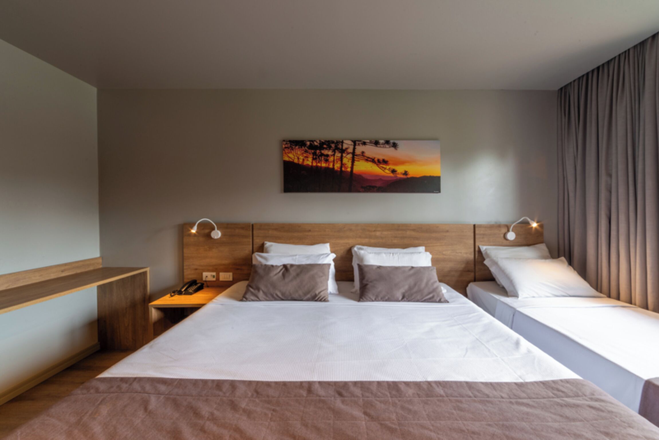 Ein Hotelzimmer mit einem großen Bett, zwei Nachttischen, einem Beistelltisch und einem Gemälde an der Wand.