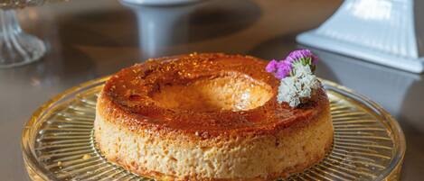 A round cake on a clear glass plate with a decorative flower on top.
