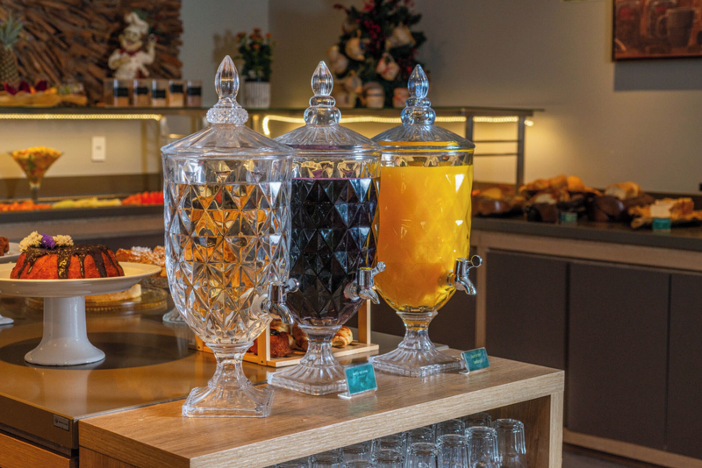 A buffet with clear glass containers holding various beverages and a selection of pastries.