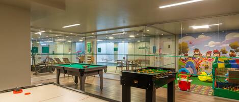A pool table, foosball table, and a children's play area with a colorful mural.