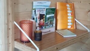 Interior de una cabaña de madera con una estantería que sostiene un libro, un cojín estampado y un objeto decorativo.
