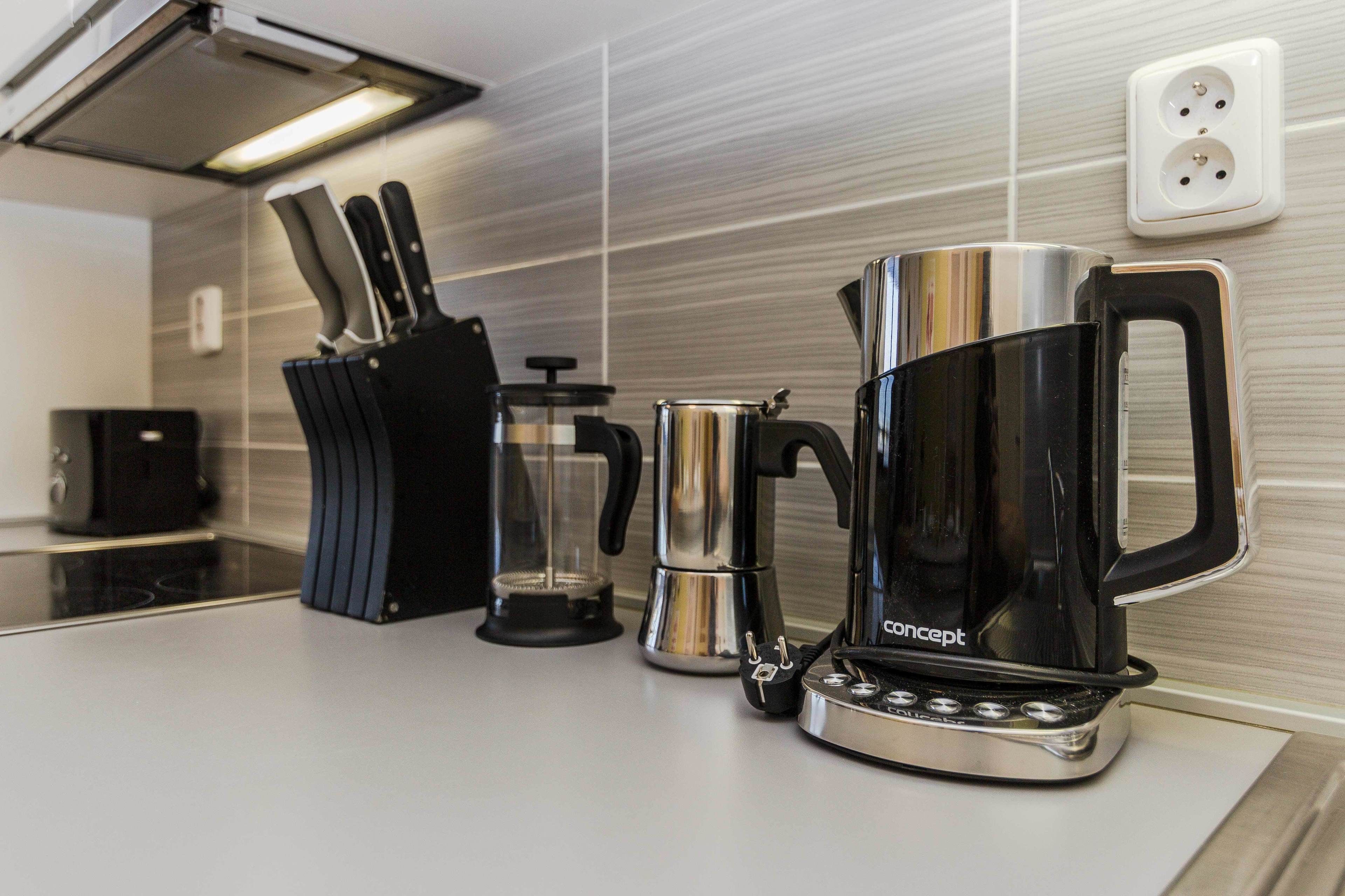 A modern kitchen with a coffee maker, a kettle, and a knife block.