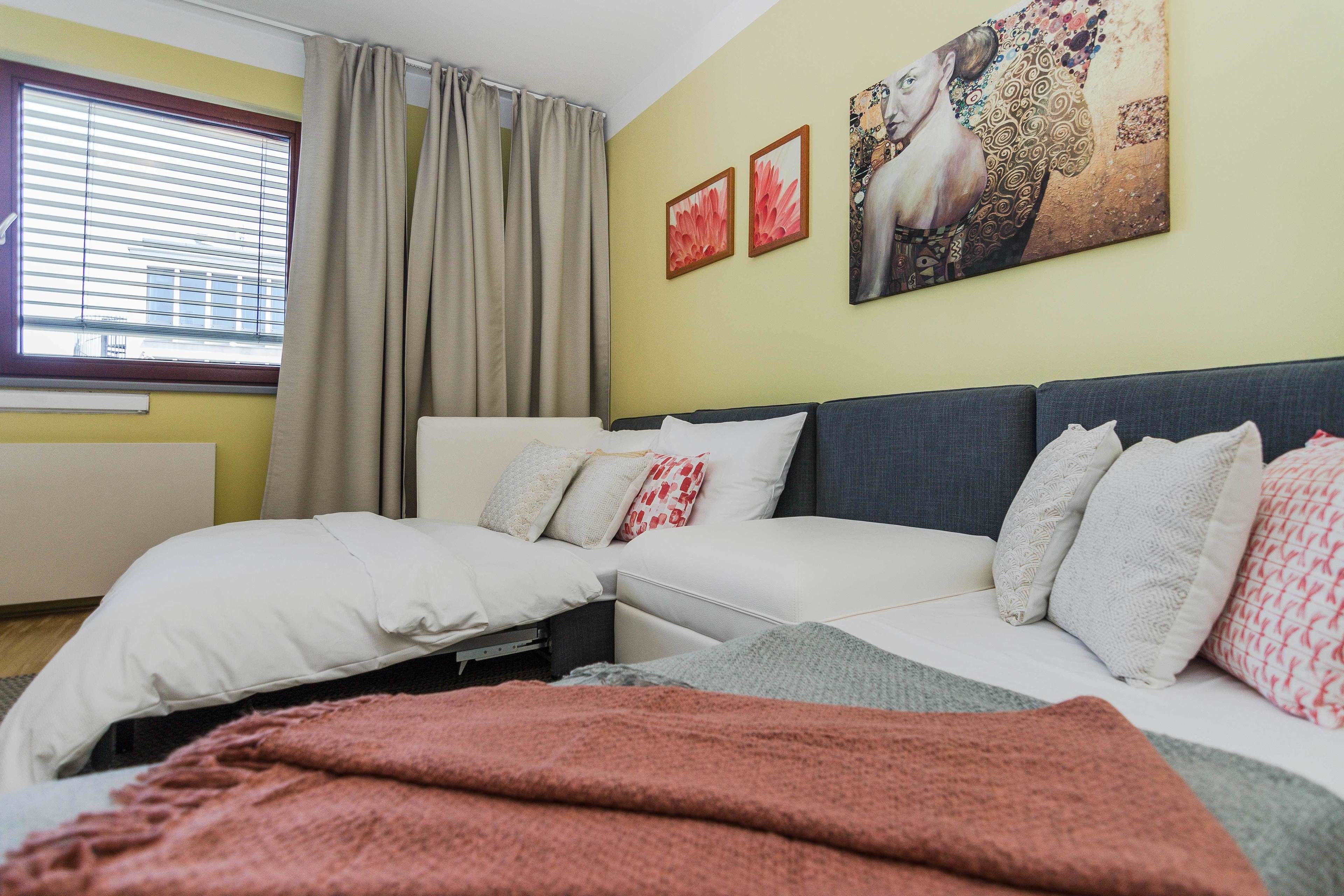 Een slaapkamer met een bed, een bank en een raam met gordijnen.