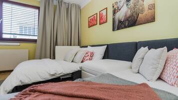 Een slaapkamer met een bed, een bank en een raam met gordijnen.