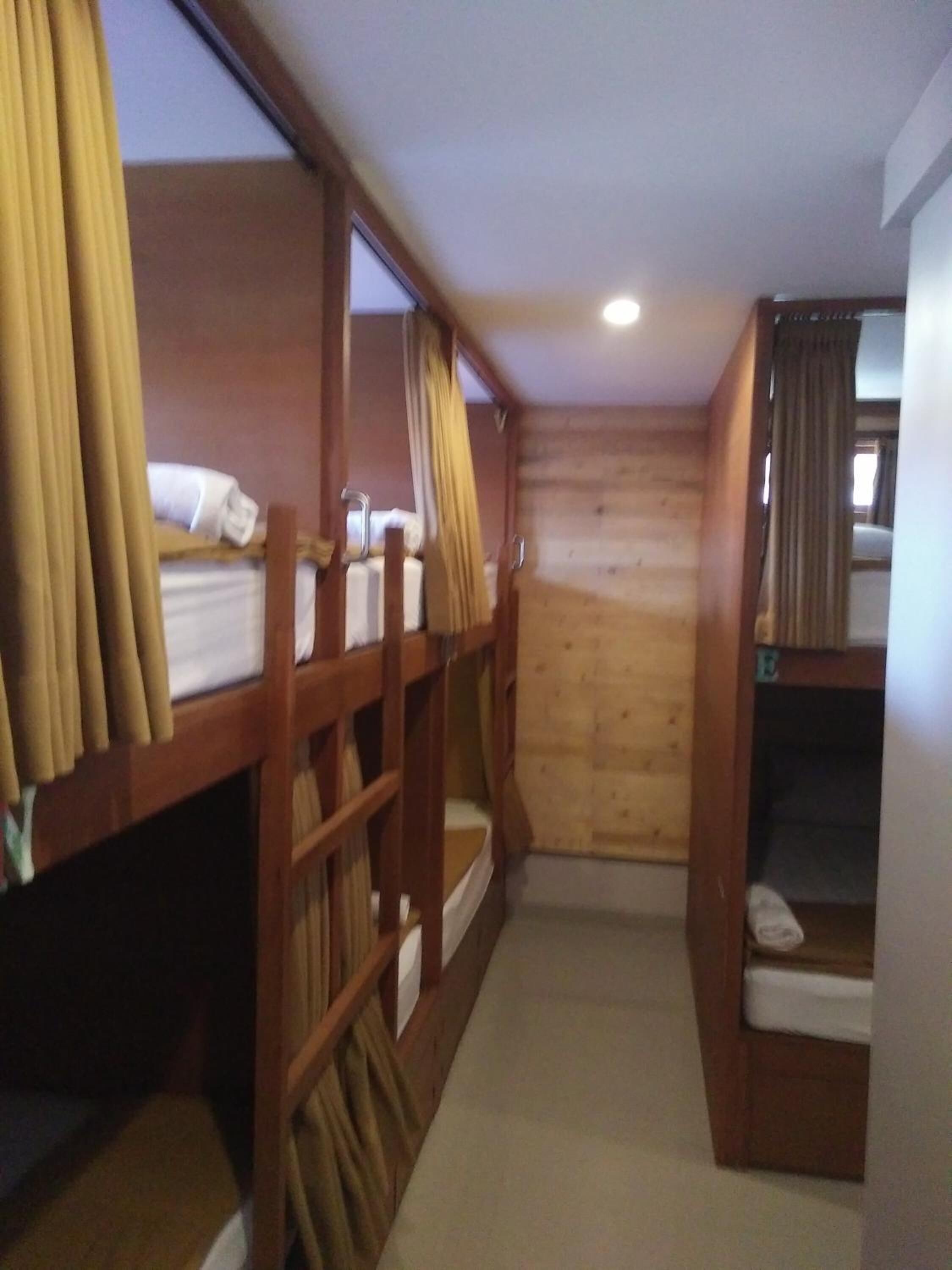 Ein Schlafsaalzimmer mit Etagenbetten, Holzwänden und einem kleinen Fenster.