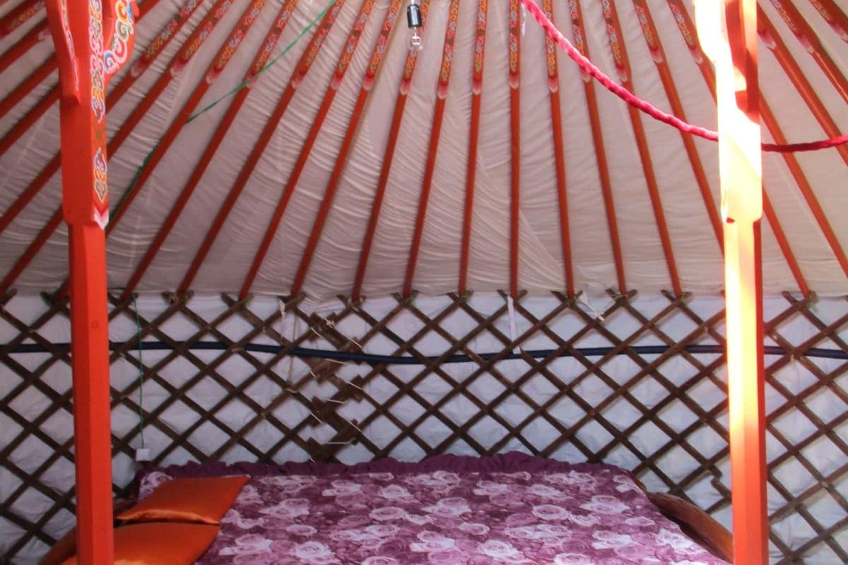 Une yourte traditionnelle avec un lit, une structure en bois et un tissu à motifs.