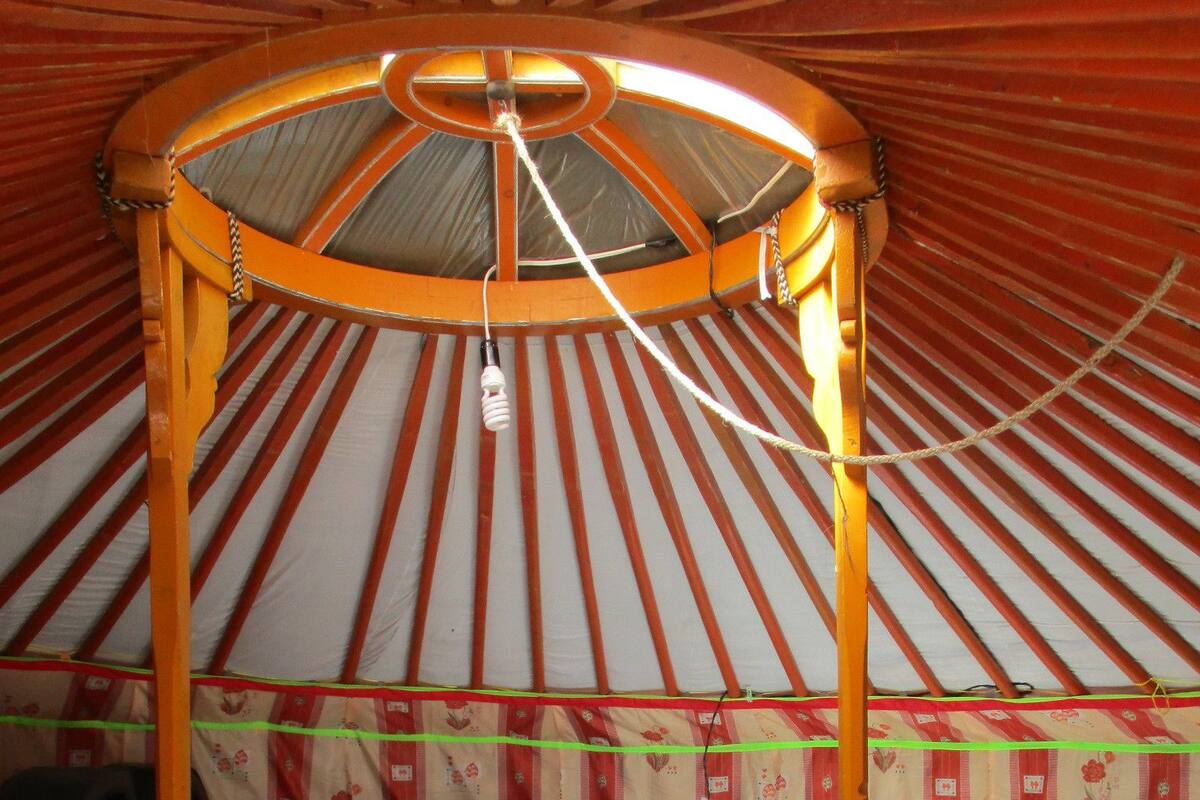 Une yourte traditionnelle avec un lit, une structure en bois et des murs décorés de motifs.