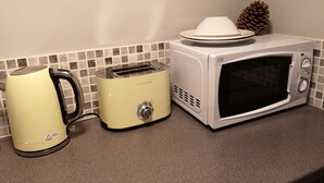 Een keuken met een magnetron, een broodrooster en een waterkoker op een aanrecht.
