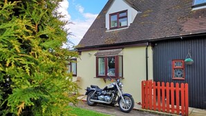 Een huis met een motorfiets ervoor, een rode picket fence en een kleine schuur.