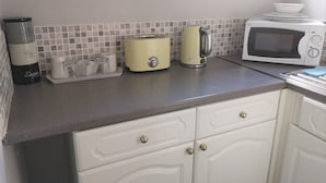 Een keuken met een magnetron, broodrooster, waterkoker en koffiezetapparaat op het aanrecht.