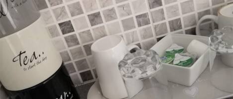 A kitchen counter with a coffee maker, a mug, and a tray with a box of tea bags.