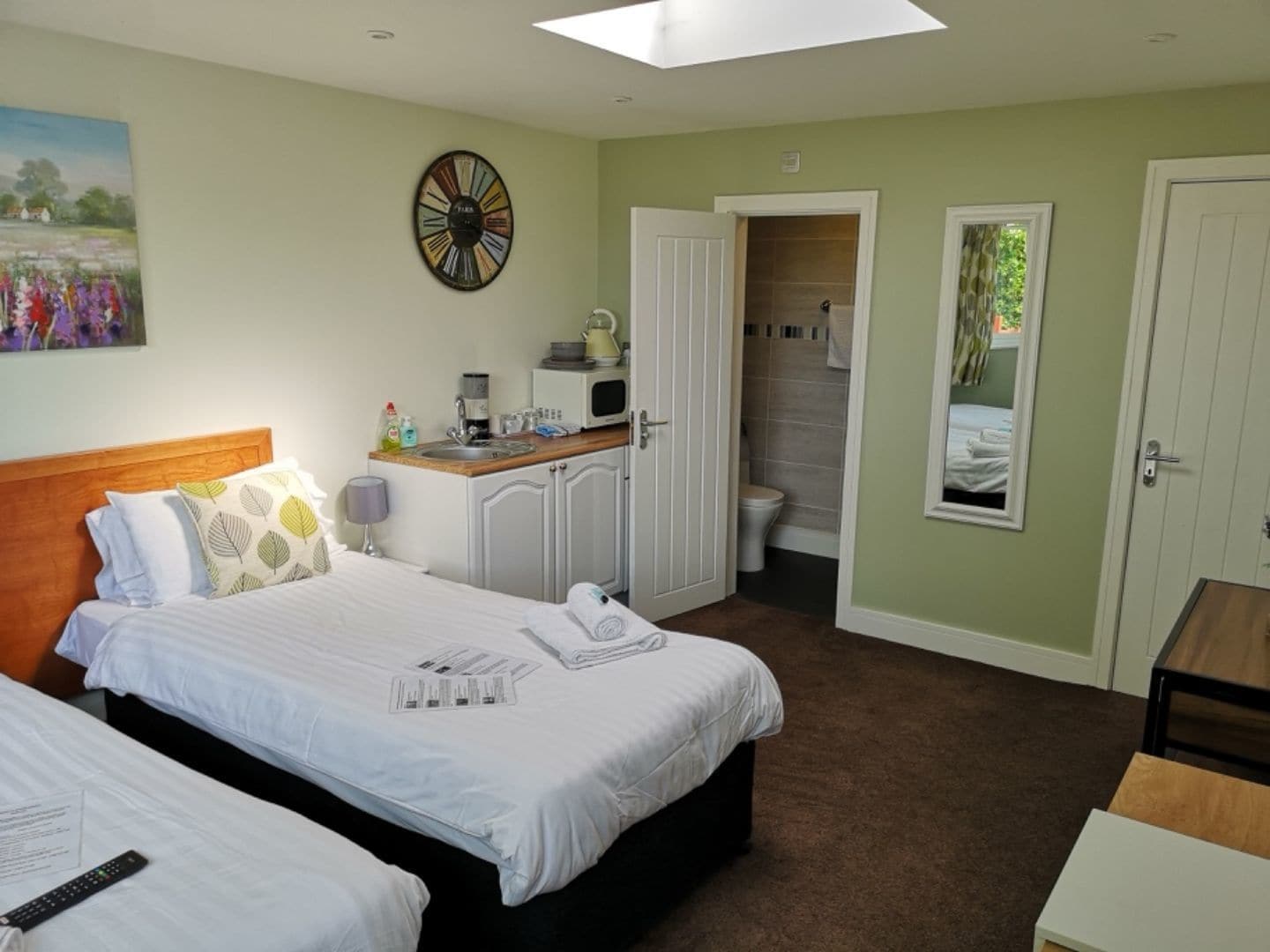 Une chambre d’hôtel avec un lit, un bureau doté d’un micro-ondes, un lavabo et une vue sur la salle de bain.