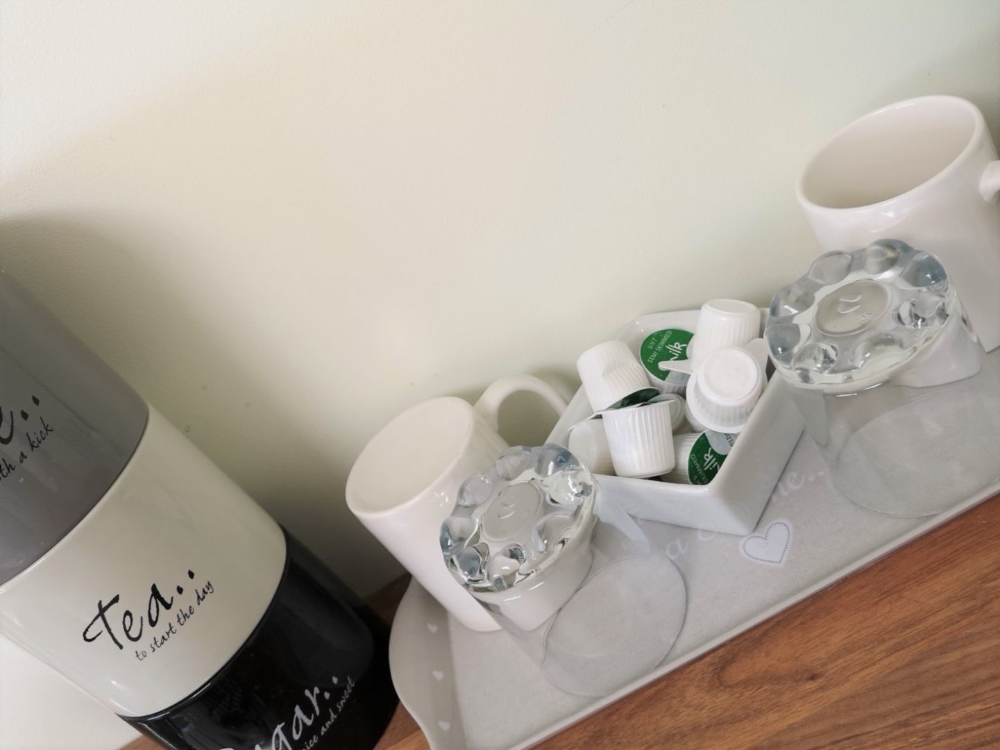 A tray with a white mug, a black bottle, and several small white bottles with green labels.