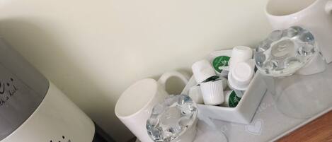 A tray with a white mug, a black bottle, and several small white bottles with green labels.