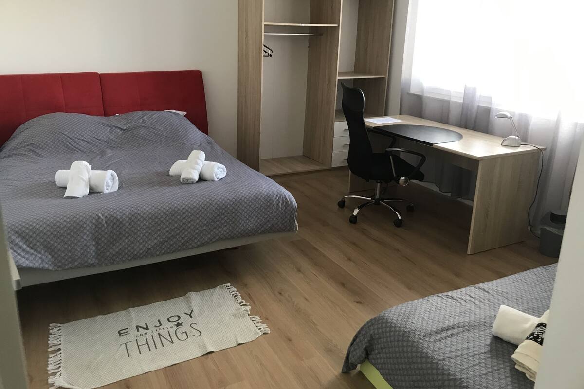 Een slaapkamer met een bed, een bureau en een kledingkast.