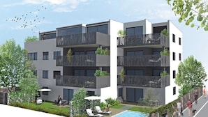 Een modern meerlaags woongebouw met balkons, een zwembad en buitenzitplaatsen.
