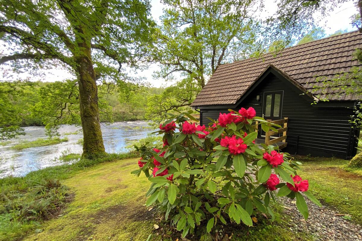 Ein rustikales Blockhaus mit einem Fluss im Hintergrund.