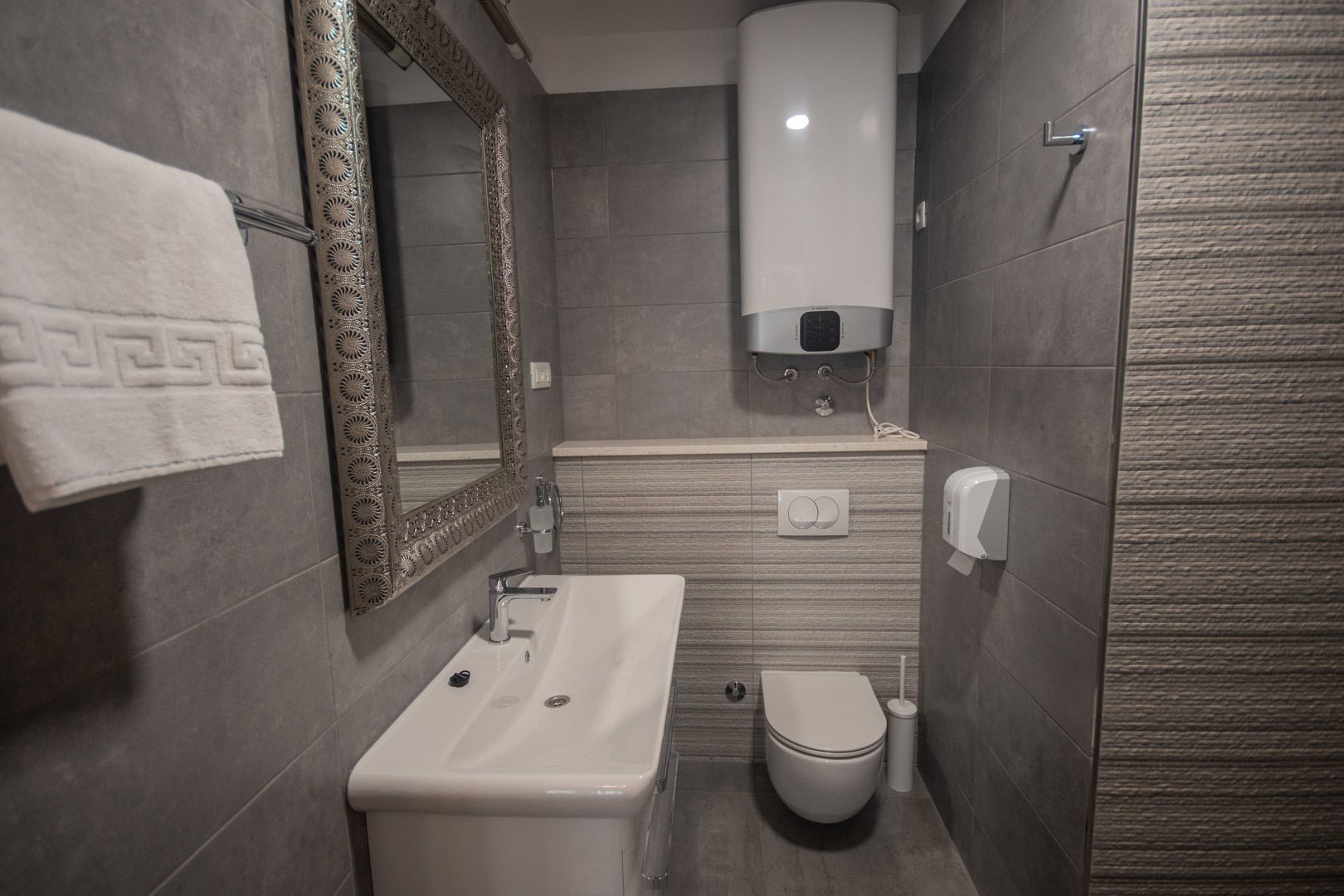 Une petite salle de bain comprenant un lavabo, des toilettes et un sèche-mains.