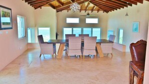 Un comedor amplio con una mesa larga y seis sillas, ventanas grandes y techo de madera.